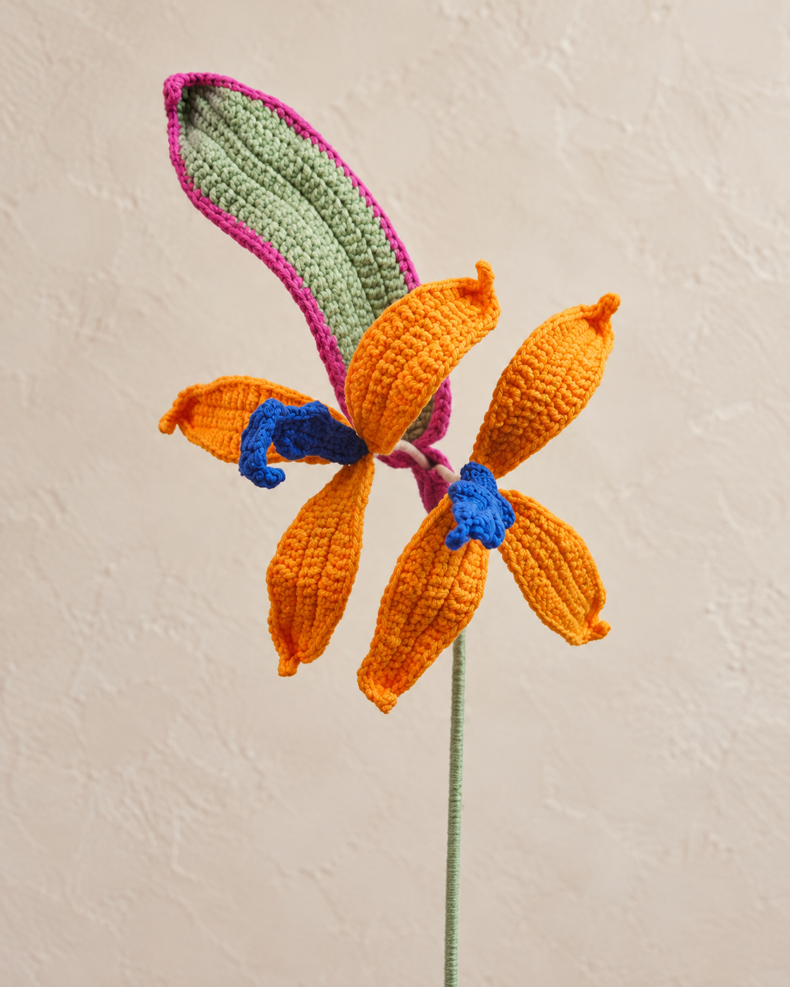 Detail of orange crochet bird of paradise petals, blue accents and pink-edged sage green bract