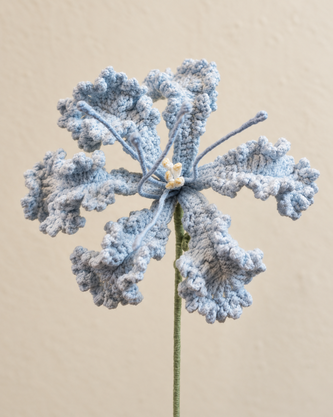 Close-up of dusty blue curled crochet petals and cream-coloured stamens