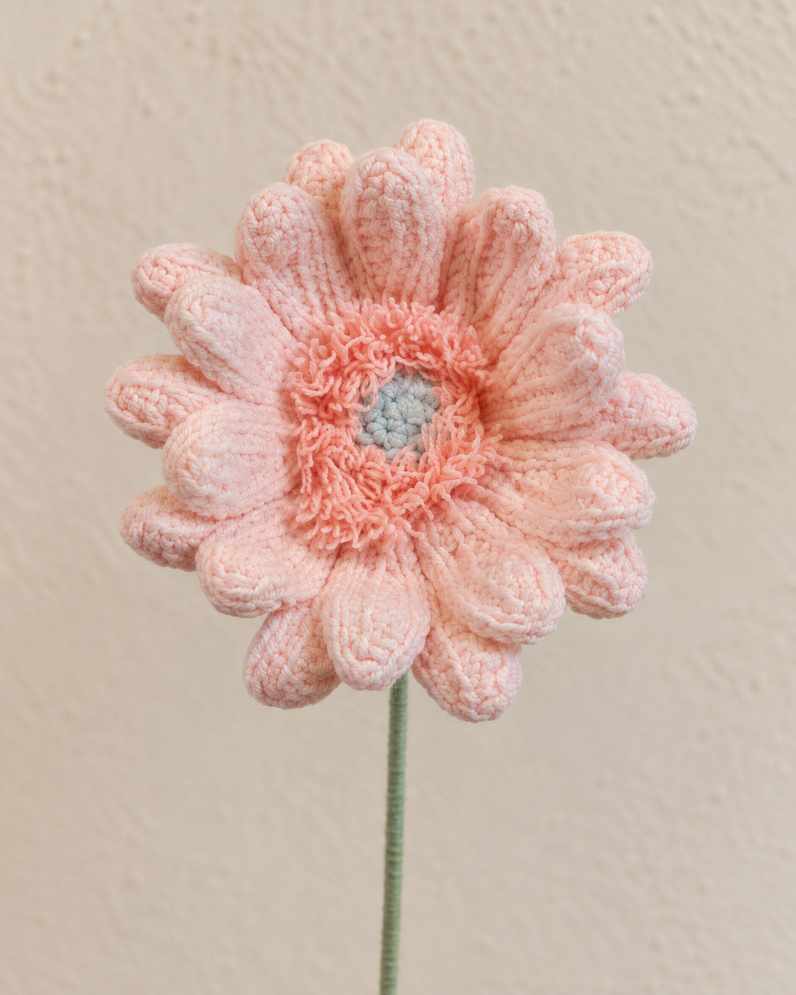 Close-up of blush pink crochet gerbera petals with peach-pink fringe and grey-blue centre